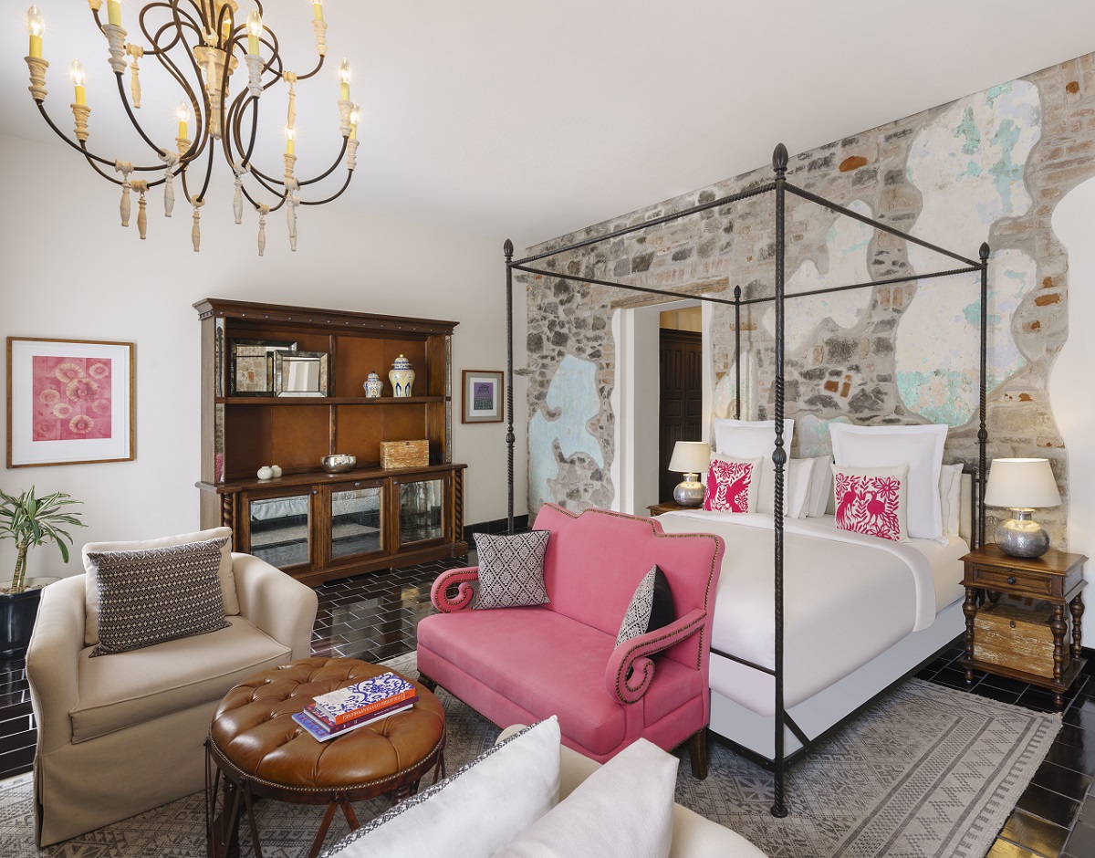 Canopy bed with pink sofa in elegant, art-filled Banyan Tree Puebla Bliss junior suite.